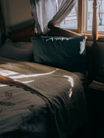 Morning light filtering through cabin windows onto cozy bedding and handcrafted quilts.