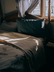 Natural light streaming through curtains onto a neat bedside table.