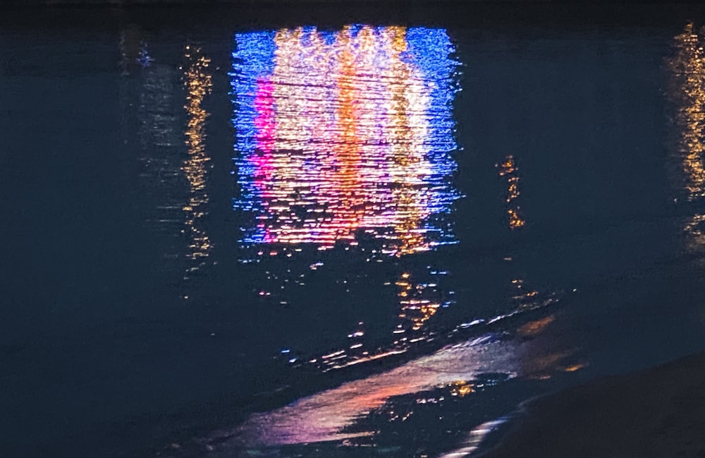 a body of water with a colorful light reflecting on it