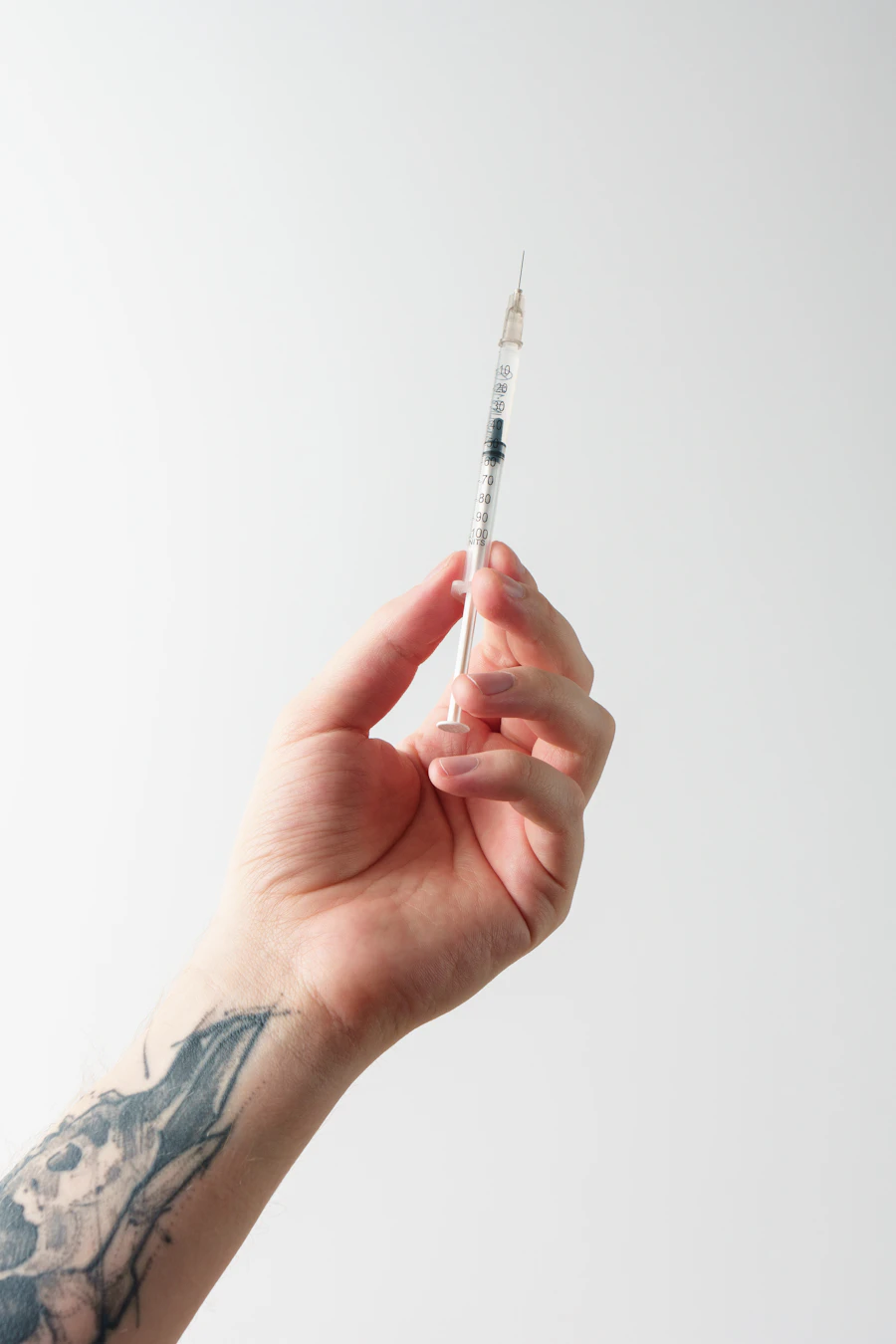 Hand holding a medical syringe in a minimalist clinical scene.