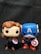 Two Funko Pop figurines are standing together against a dark background. The figurine on the left features a character with brown hair and a Union Jack design on the chest, holding a shield with a similar pattern. The figurine on the right depicts a character in a blue costume with an 'A' on the forehead and a star emblem on the chest, holding a red, white, and blue shield.