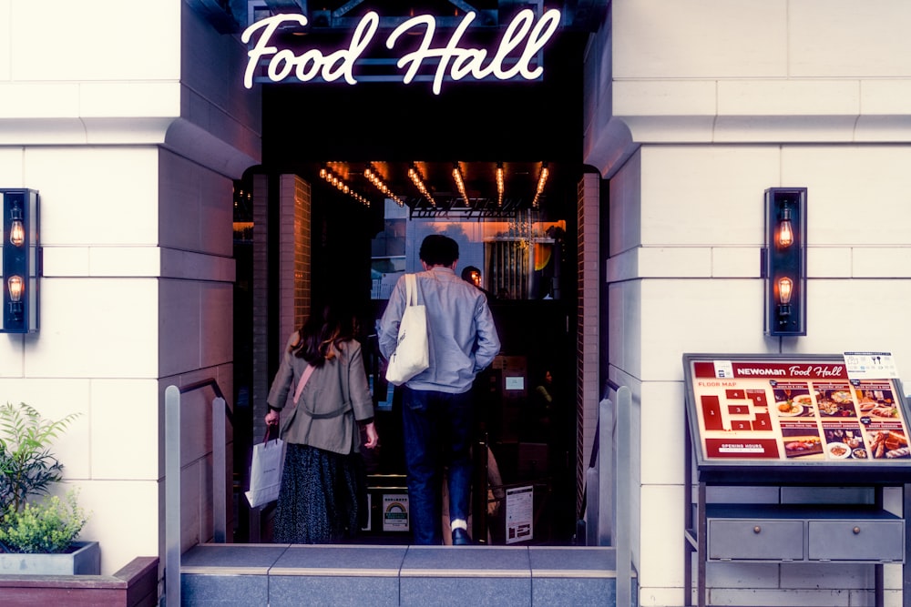 a man and woman standing in front of a storefront