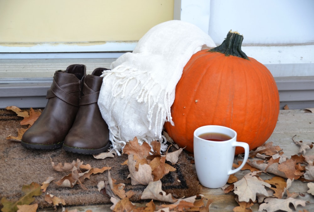 a pair of boots next to a pumpkin and a cup of coffee