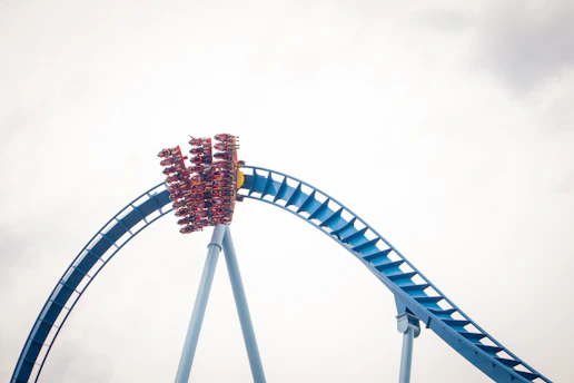 A thrilling roller coaster twisting through a bright blue sky with happy riders.