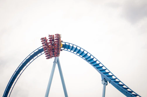 A thrilling roller coaster twisting through a bright blue sky with happy riders.