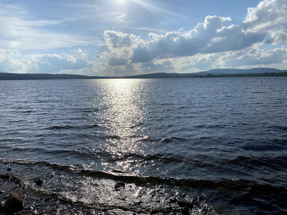 a body of water with rocks and a cloudy sky