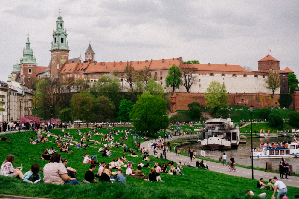 a large crowd of people sitting on the grass in front of a large building