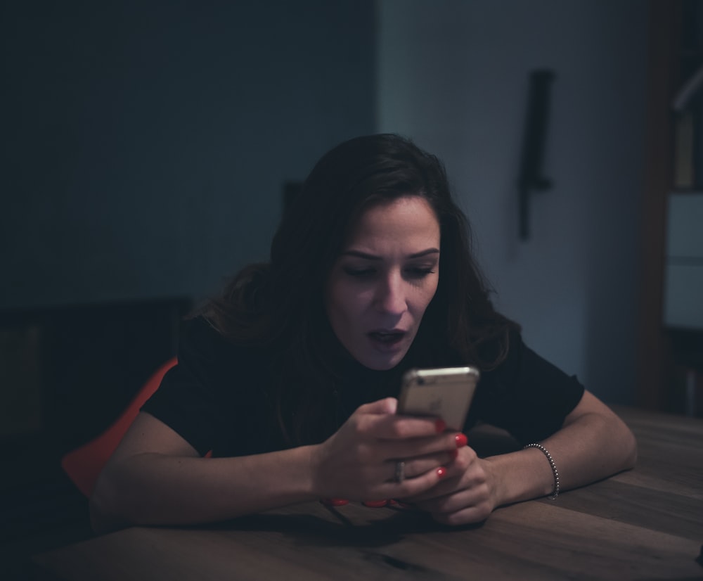 a person sitting at a table and looking at a phone