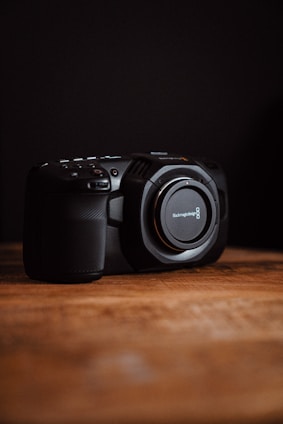 A professional digital camera displayed on a wooden table with natural light highlighting its details.