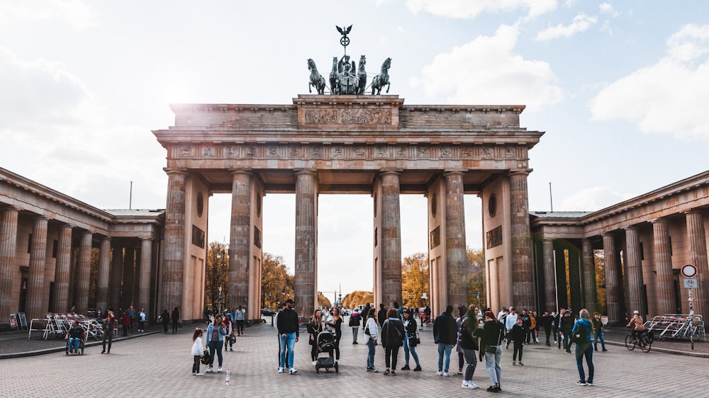 a large stone arch with columns and statues on top with Brandenburg Gate in the background