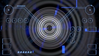 A futuristic digital display featuring geometric shapes, concentric circles, and circuit-like patterns. Various lines and circular elements are spread across a dark background, giving a high-tech appearance.
