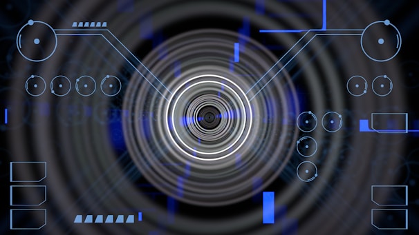 A futuristic digital display featuring geometric shapes, concentric circles, and circuit-like patterns. Various lines and circular elements are spread across a dark background, giving a high-tech appearance.