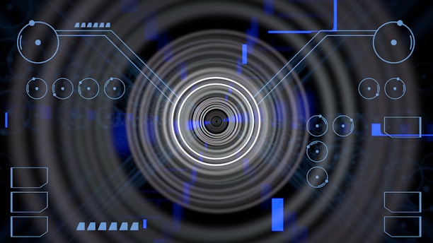 A futuristic digital display featuring geometric shapes, concentric circles, and circuit-like patterns. Various lines and circular elements are spread across a dark background, giving a high-tech appearance.