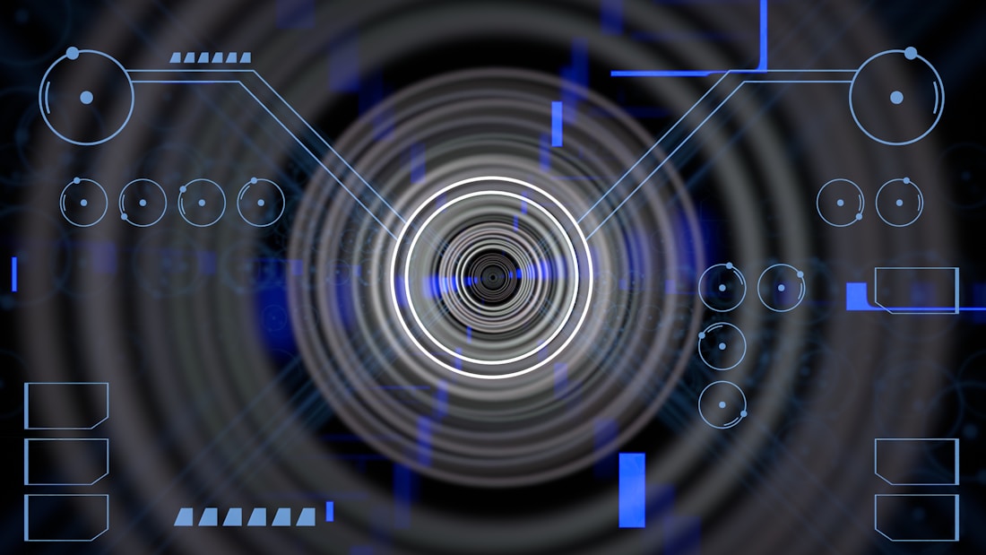 A futuristic digital display featuring geometric shapes, concentric circles, and circuit-like patterns. Various lines and circular elements are spread across a dark background, giving a high-tech appearance.
