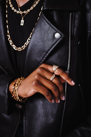a person wearing a black jacket and gold jewelry