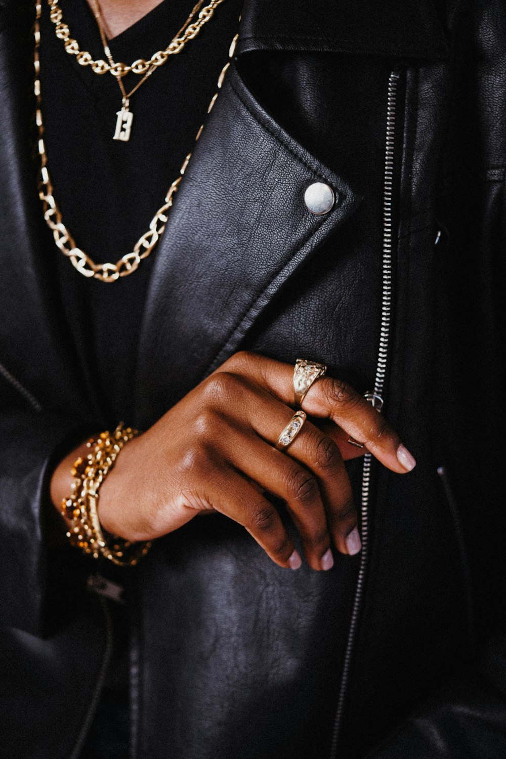 a person wearing a black jacket and gold jewelry