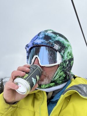 a person wearing a helmet and goggles drinking from a can