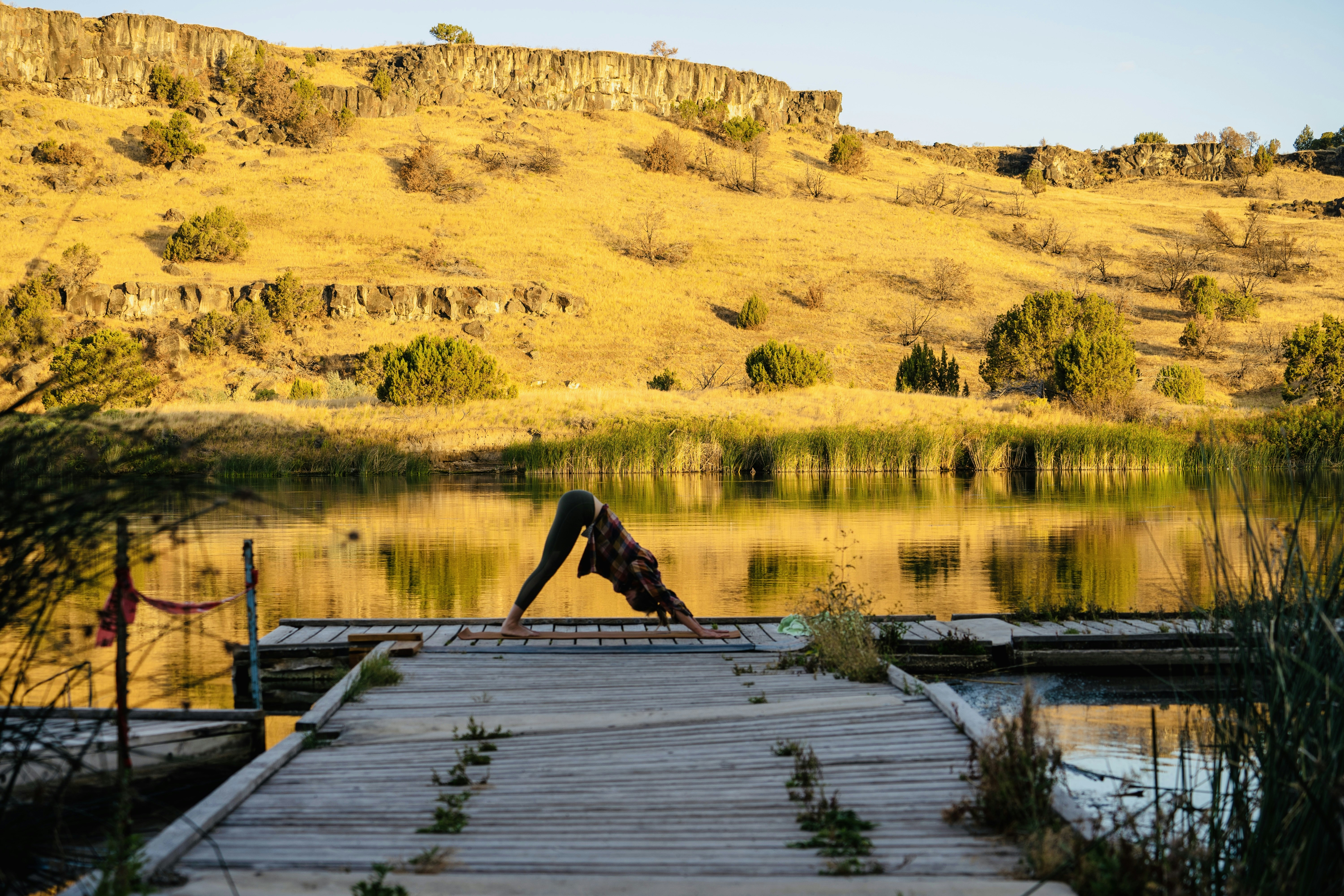 a wooden dock over a body of water with hills in the background