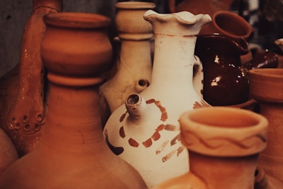 A collection of various clay pots in earthy tones, featuring different shapes and sizes. The image emphasizes textures and patterns, highlighting the craftsmanship of pottery.