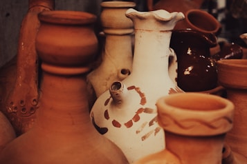 A collection of various clay pots in earthy tones, featuring different shapes and sizes. The image emphasizes textures and patterns, highlighting the craftsmanship of pottery.