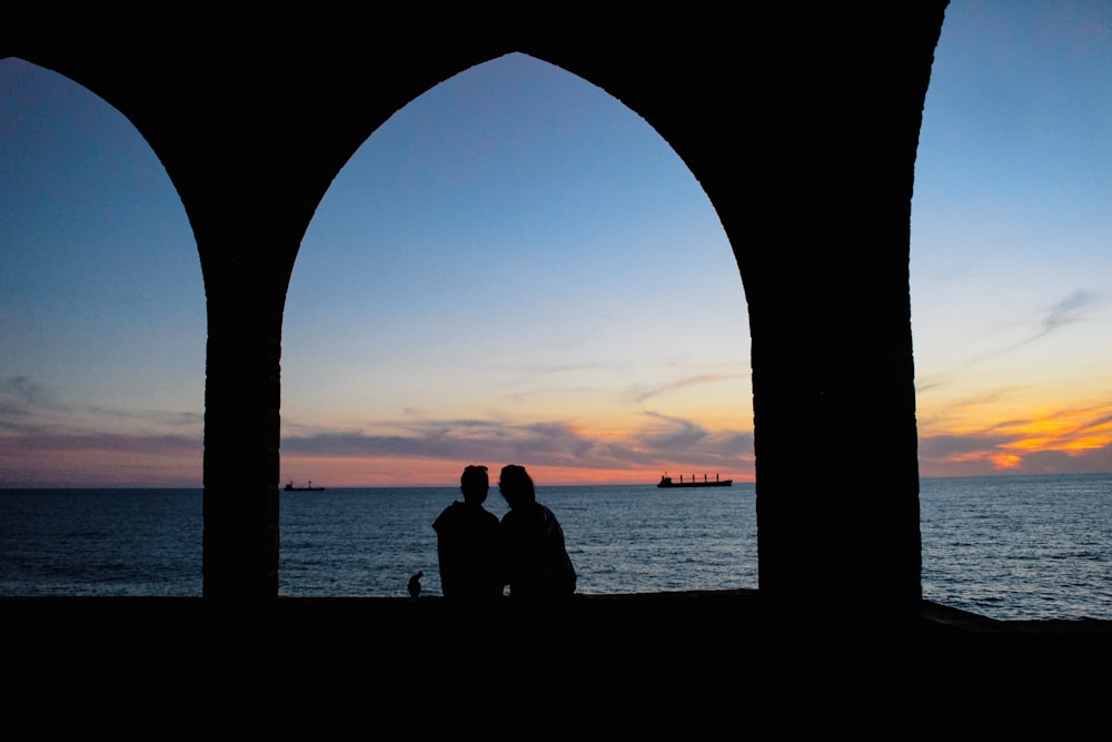 a couple sitting on a bench looking out at the ocean