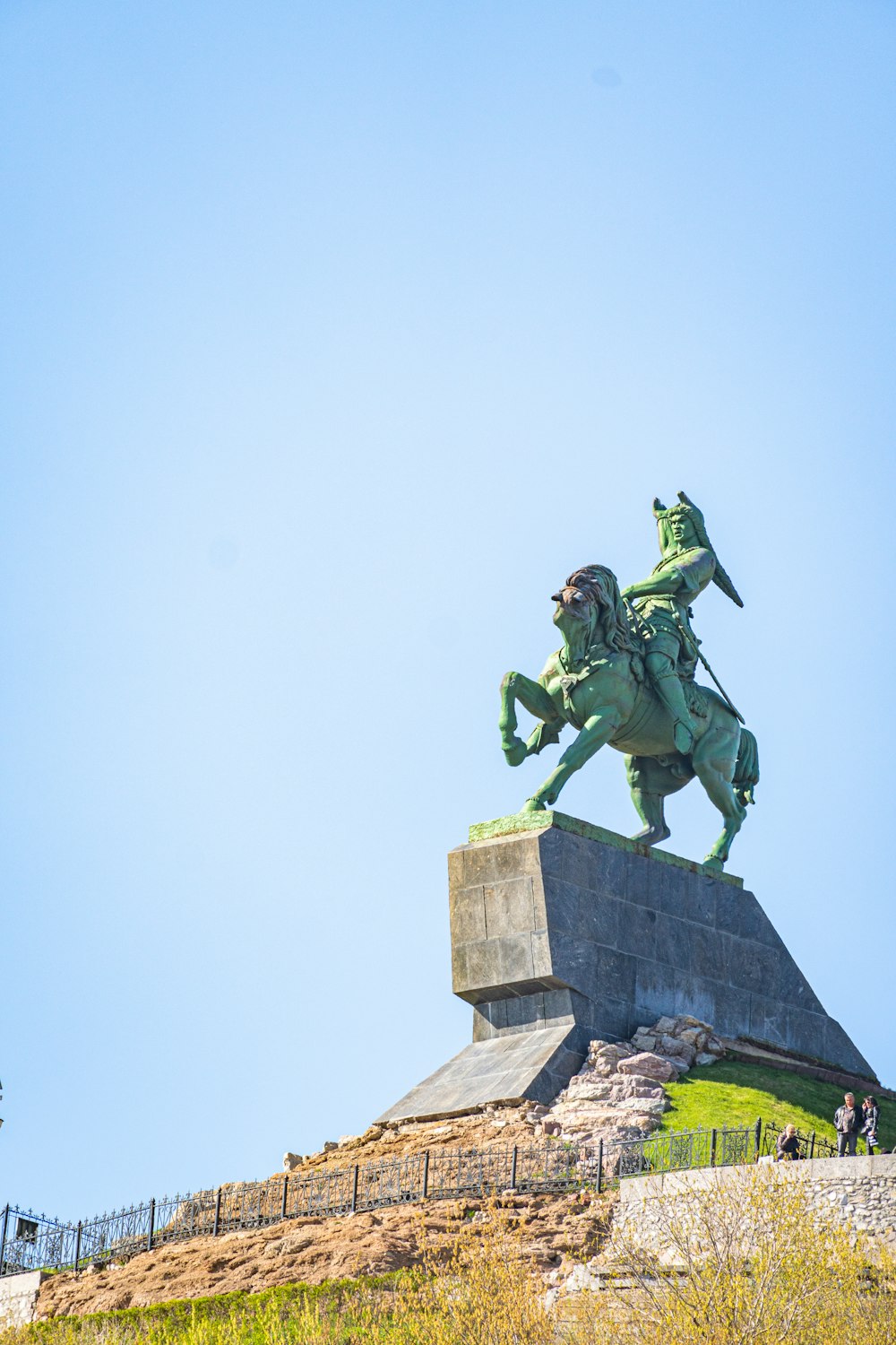 Eine Statue einer Person, die auf einem Pferd auf einer Steinmauer reitet