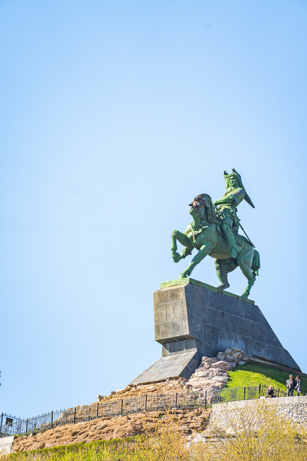 a statue of a person riding a horse on a stone wall