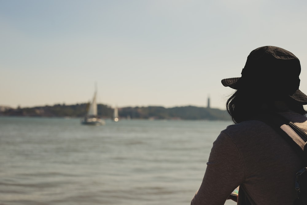 a person looking at a sailboat on the water