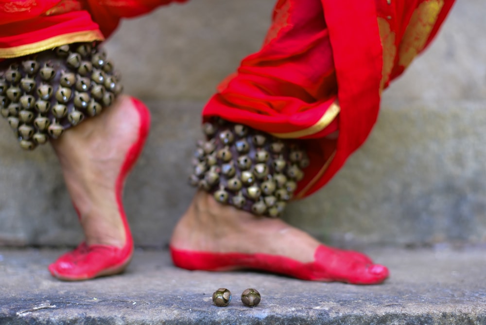uma pessoa vestindo sapatos vermelhos e segurando um cacho de uvas