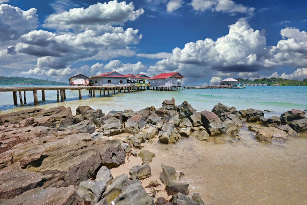 a rocky beach with a pier and buildings in the background