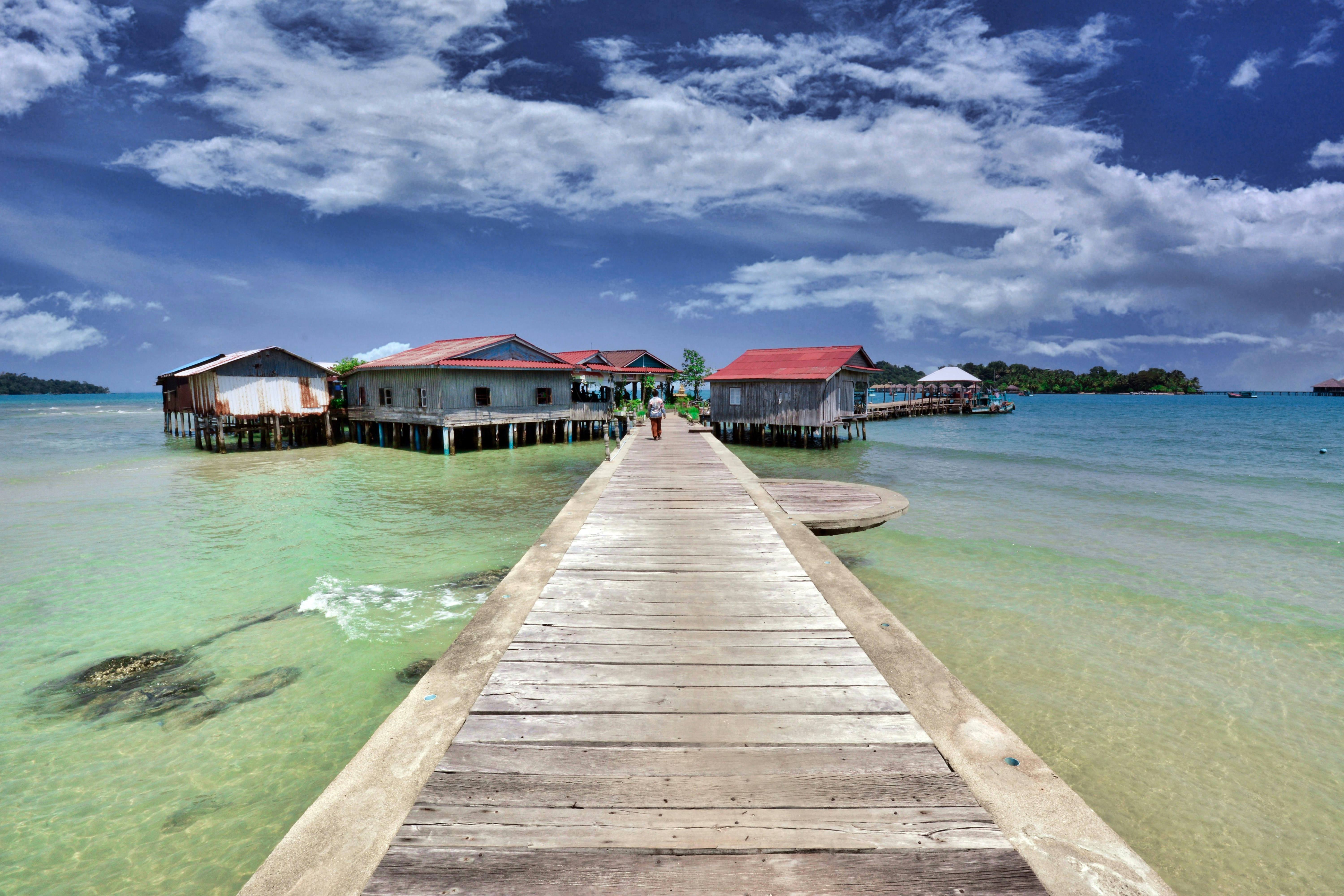 a dock leading to a building on the water,  Fishing pier in Cambodian island of Koh Rong