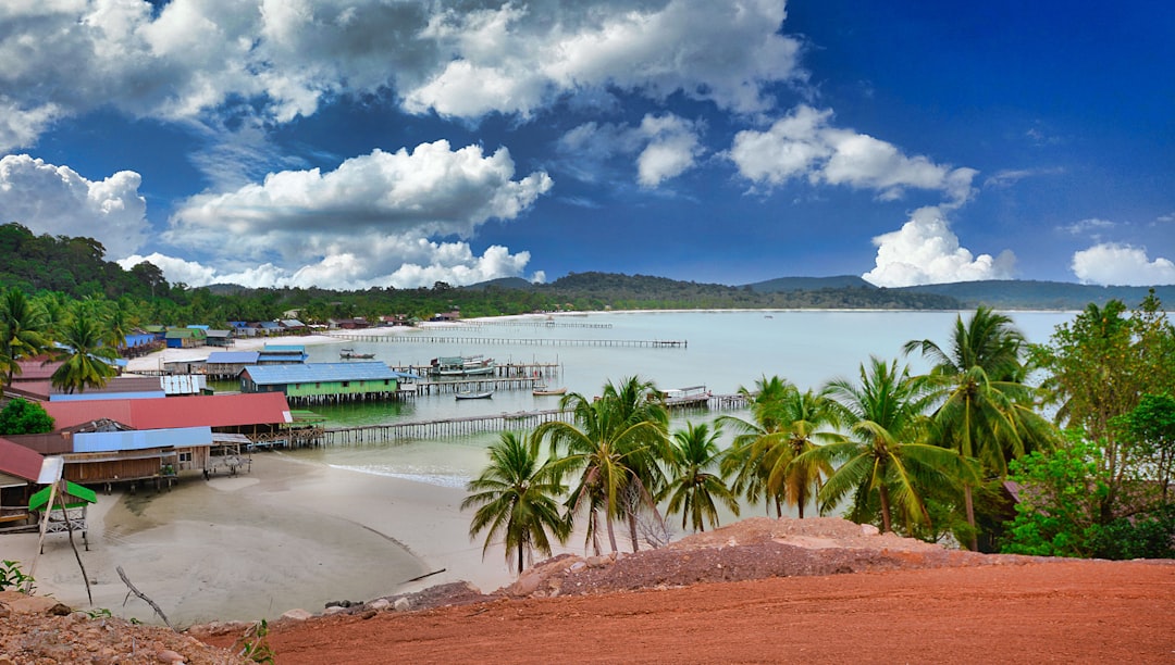 a beach with palm trees and a body of water, tropical Island fishing village - view from a hill