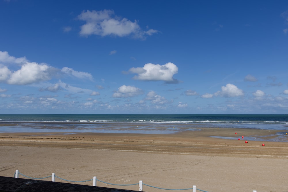 a beach with a fence and a body of water in the background