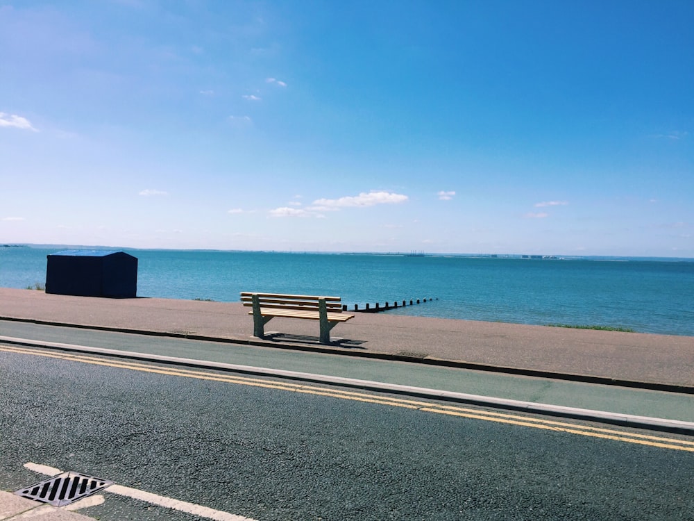 a bench on the side of a road by the water