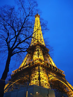 A twilight view of the Eiffel Tower glowing against a deep blue Parisian sky.