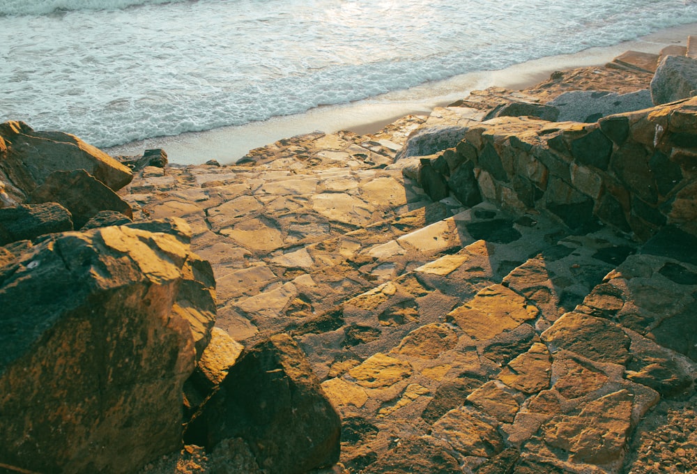 a rocky beach with a body of water in the background