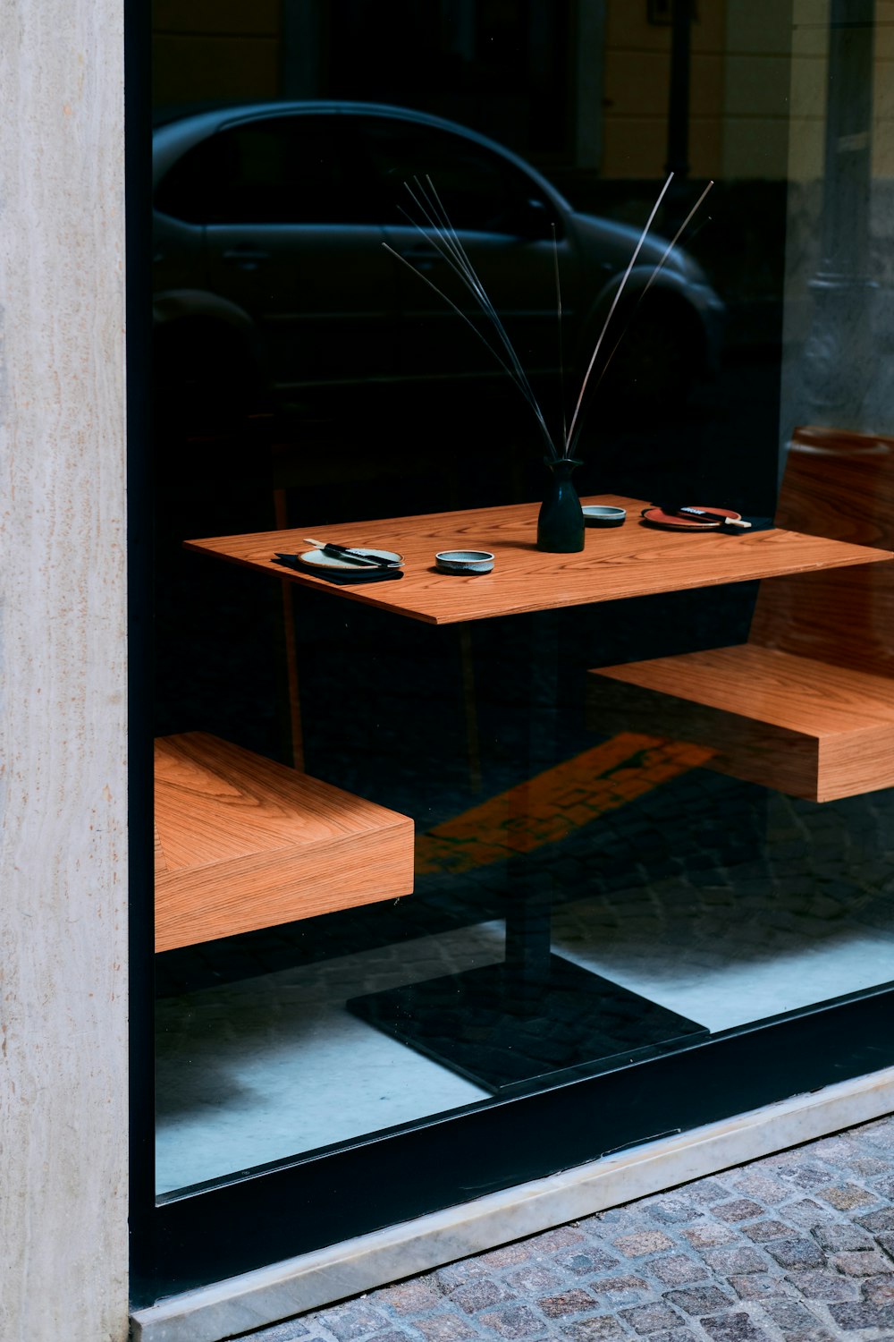 a glass window with a vase of flowers on a table