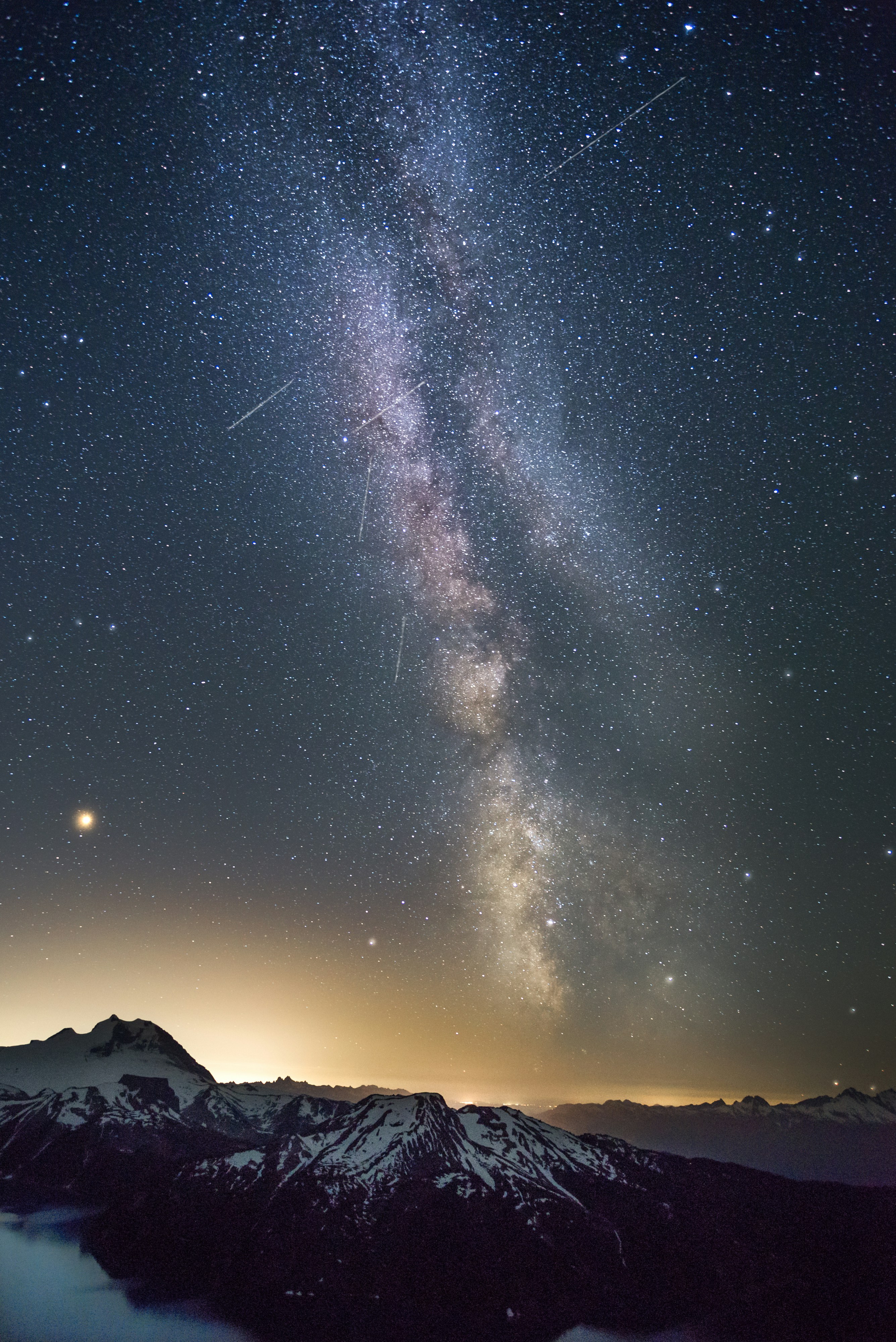 a mountain range with a bright light in the sky