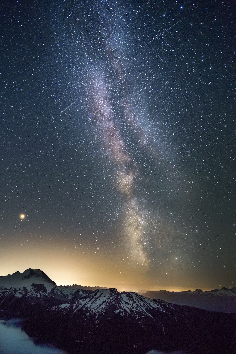 a mountain range with a bright light in the sky