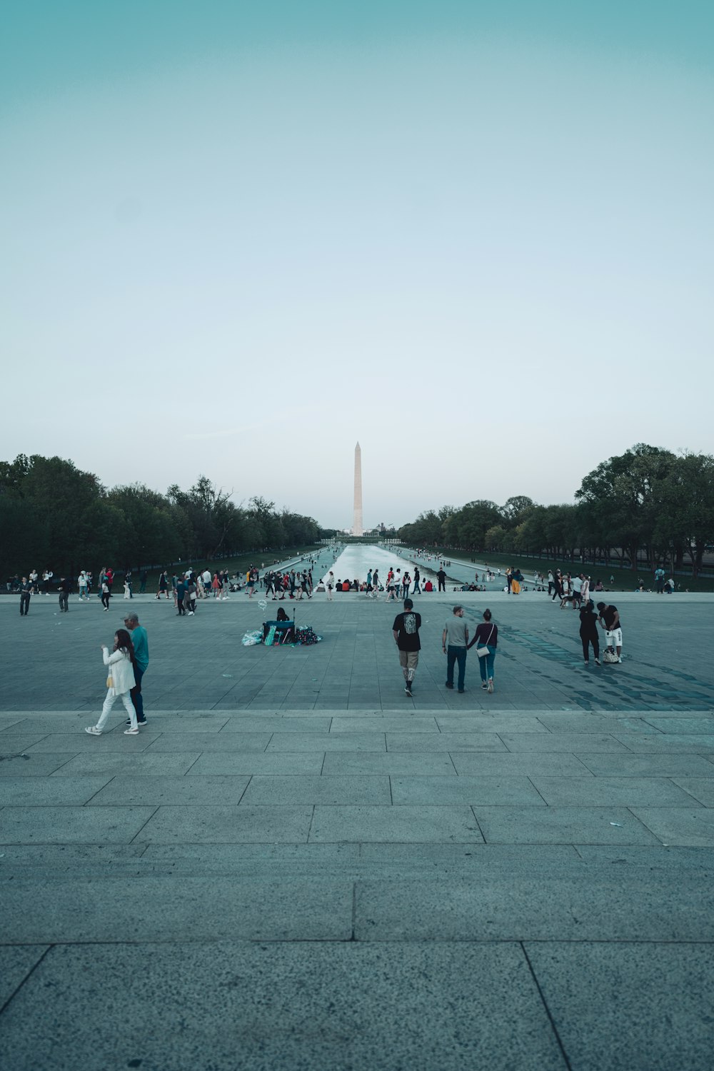 a group of people walking around a large courtyard with a monument in the background