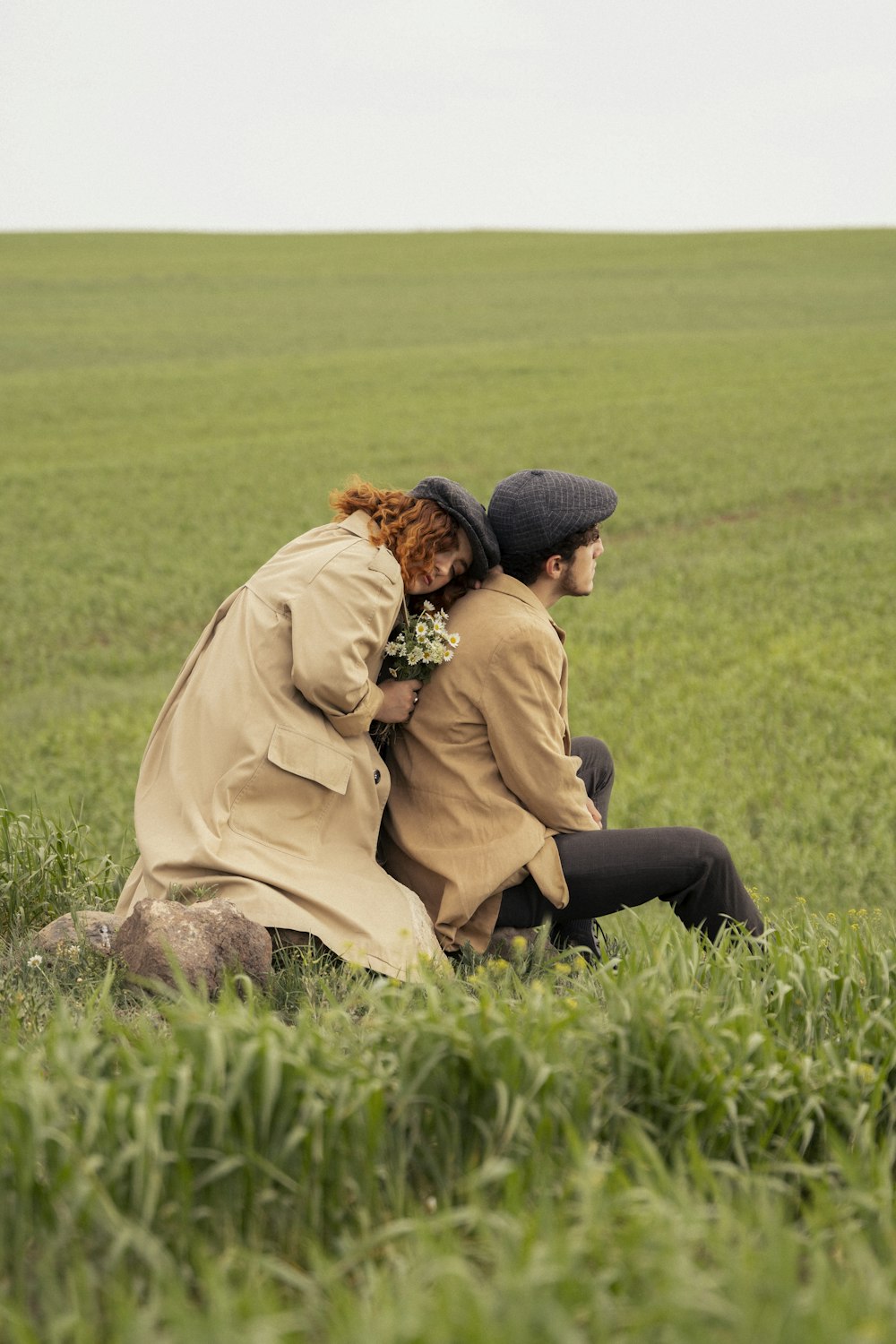 a man and woman sitting in a field of grass