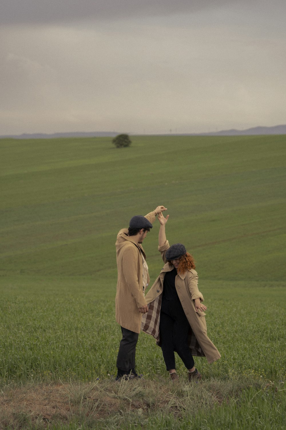 a man and woman standing in a field with a man holding a woman's hand up