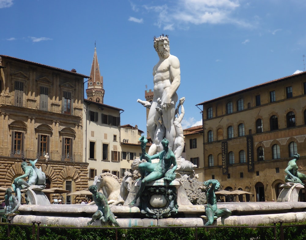 une statue dans une cour avec des bâtiments en arrière-plan avec la fontaine de Neptune, Florence en arrière-plan