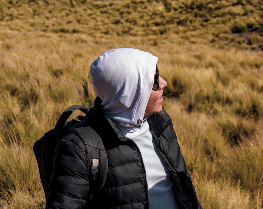 a man wearing a hoodie and a backpack in a field