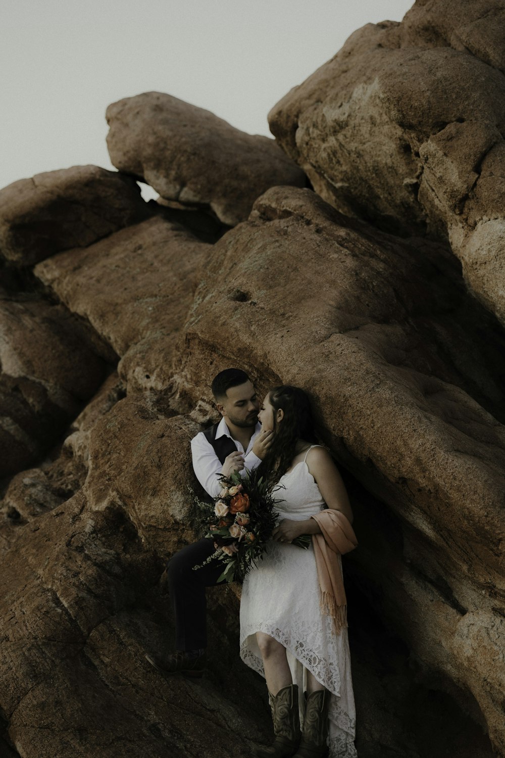 a man and woman posing for a picture in front of a large rock