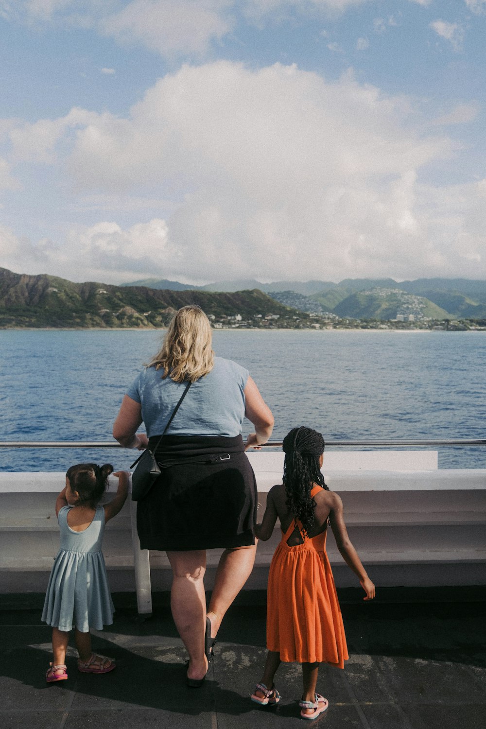 a woman and two children looking at a body of water