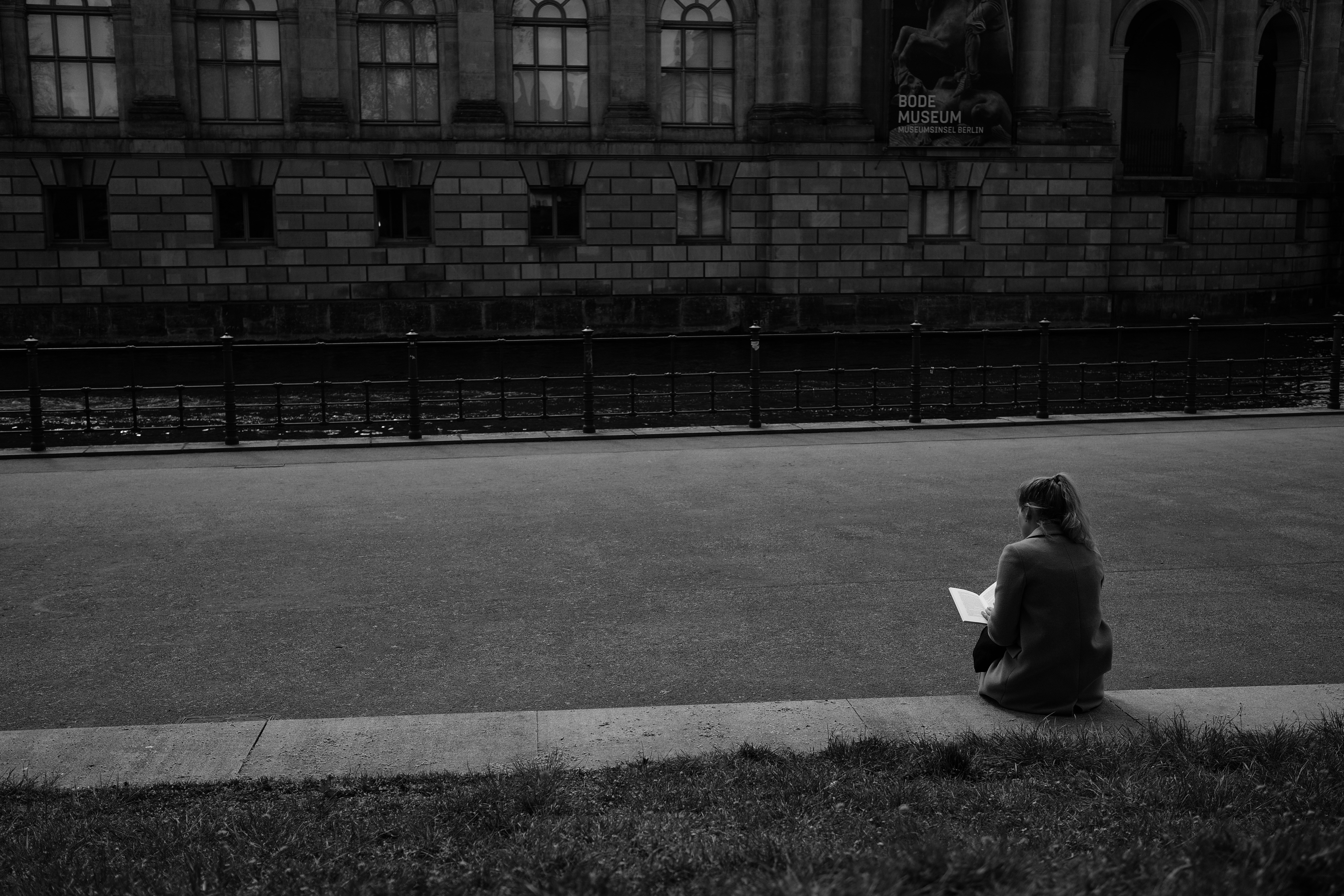 Person reading book by roadside