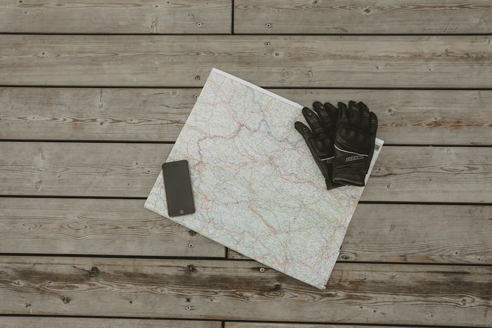 a pair of black gloves on a white piece of paper on a wood surface