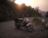 An outdoor scene with a classic Siambretta parked beside a rustic wall, bathed in golden hour light.