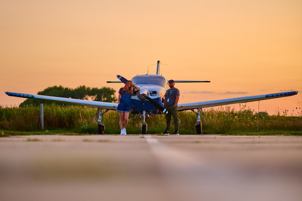 a couple of people standing next to a small plane